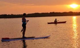 A kayaker and a paddle boarder enjoying sunset over the river in St. Augustine.