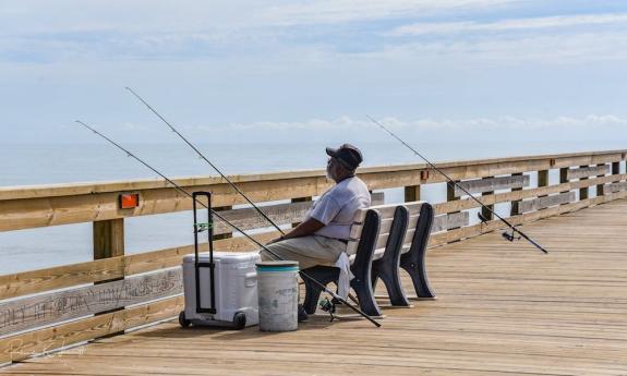 A man fishing at the dock near the park