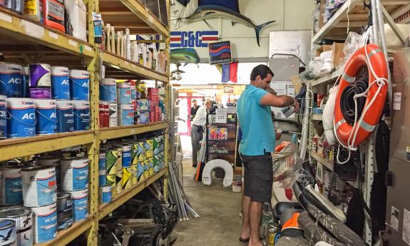 A customer looks through Sailor's Exchange with a wall of boat paints behind him.