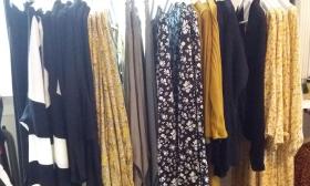 A rack of women's clothing in blues and soft yellows at Wild Raven in St. Augustine.
