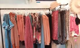 Clothing in corals, soft reds, and denim, on the rack at Wild Raven Boutique in St. Augustine.
