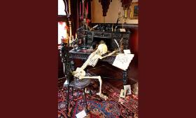 A skeleton sits at a desk in the Victorian Halloween exhibit at Villa Zorayda.