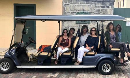 Gold Tours with their green large EV, on a St. Augustine Street with clients aboard
