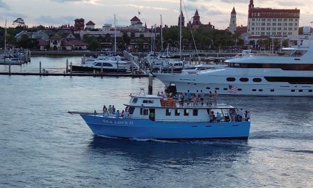 Sea Love II, a blue charter fishing and party boat, cruising past the City of St. Augustine