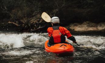 A person uses a paddle to wade through water. 