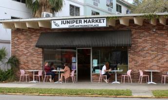 The exterior of Juniper Market with cafe tables and chairs