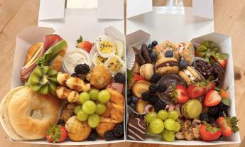 Graze boxes featuring bagels, grapes, berries, cheeses, and kiwis.