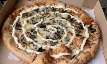 A Holy Shiitake pizza in a to-go box