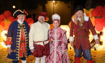 St. Augustine's Royal Family in front of an illuminated sign at the Spanish Food and Wine Festival