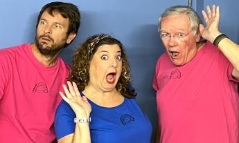 Two improvisers in pink t-shirts with an improviser in a blue t-shirt in the middle
