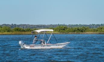 A fishing boat with a Bimini top, underway on the Matanzas River