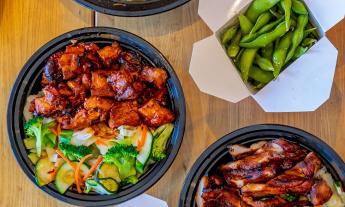 Bowls of meats and veggies with a container of edamame on the side
