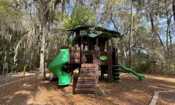 The playground area is shaded with plenty of trees