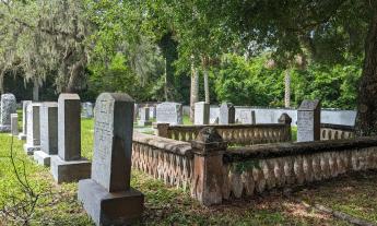 This old section of a cemetery includes a family plot surrounded by a low cast concrete fence
