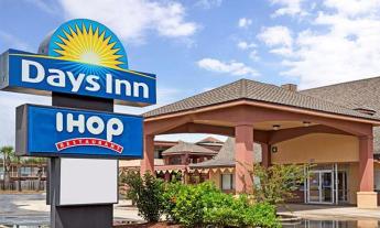 The entrance to the Days Inn on SR 16 in St Augustine, FL on a clear day with blue skies. A sign stands in the front with the Days Inn logo and the iHop logo