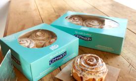 Cinnabon rolls with icing on top in boxes.