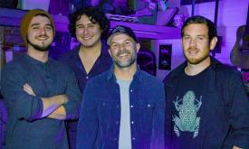 Four members of the band Tru Phonic pose inside of a purple room