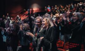 Two women standing an applauding in an audience at the St. Augustine Film Festival