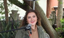 Singer-songwriter Sage Trunnell standing under trees in front of microphone