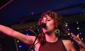 Miriam Morelli singing onstage at night, behind a microphone