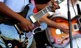 Two men playing guitars on stage, focused on the guitars and their hands
