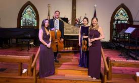 The four members of the Astralis quartet, standing in front of a harpsichord 