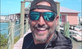 Mike Cook in sunglasses and cap, on a dock