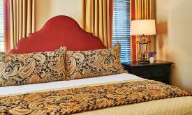 A welcoming bedroom in gold and red, can be found at the Collector Luxury Inn in St. Augustine.