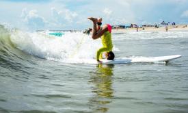 boy headstanding on surfboard