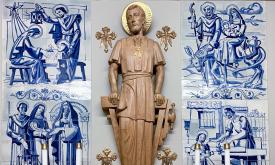 A close-up of the Chapel to Saint Joseph in the Cathedral Basilica of Saint Augustine in St. Augustine, Florida. The wooden sculpture is hand-carved and shows the saint leaning on a carpentry tool. The sculpture is backed by blue and white tiles that depict scenes from Joseph’s life.