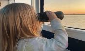 A young girl with binoculars enjoying a Florida Water Tour at sunset in St. Augustine.