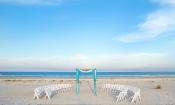 A wedding on the beach awaits with white chairs and a colorful awning at Guy Harvey Resort St. Augustine Beach.