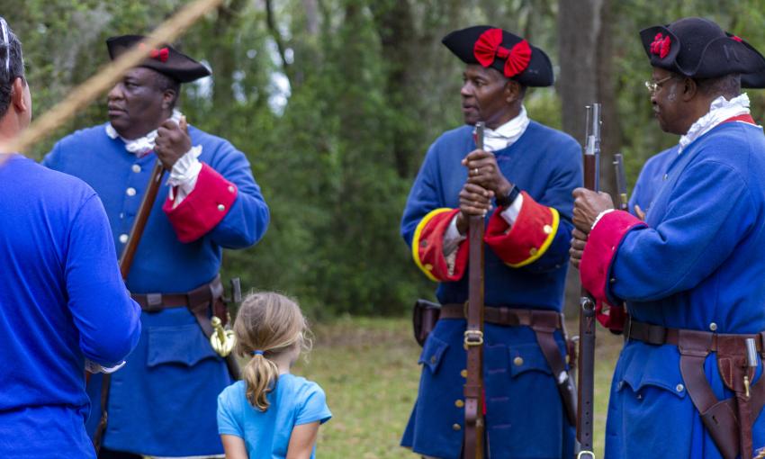 A young girl meets reenactors of the Fort Mose Militia