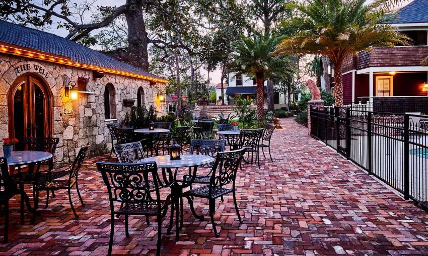 The brick courtyard and outdoor seating guest area between the pool and bar at The Collector