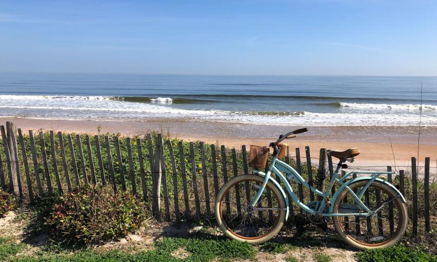 A rented bike, leaning on a fence by the beach on the First Coast