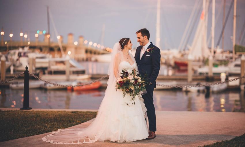 A wedding couple gazing at each other in front of the marina and Bridge of Lions, taken by Bowtie Photo