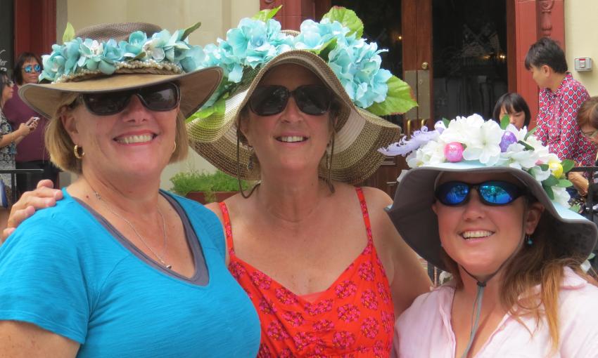 Three women, wearing sun hats decorated for the Easter Promenade 