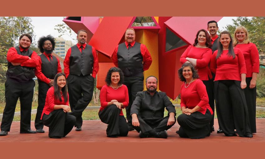 Eleven members of Voices of Jacksonville, wearing bright red and black, arrayed around their director