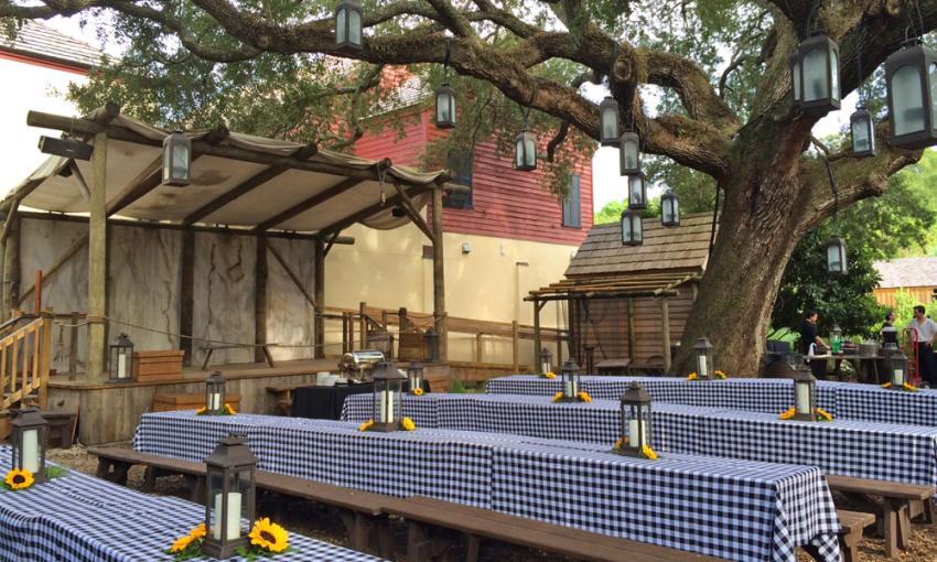 The Colonial Quarter, arranged for a reception with tables sporting blue-checked cloths under the massive oak tree
