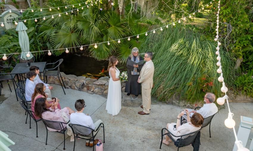 A small wedding captured from a balcony, with guests, officient, and bridal couple as seen from above